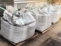 Rząd dużych worków big bag, każdy o pojemności ok. 1 m3, ustawionych na paletach.