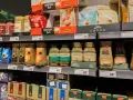 Półka sklepowa z kawą mieloną i rozpuszczalną. Gdzie wyrzucić opakowanie po kawie mielonej? Zazwyczaj do plastiku lub papieru, zależnie od materiału.