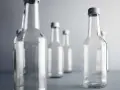 Kilka pustych szklanych butelek na szarym tle. Zastanawiasz się, jak długo rozkłada się szkło? To wieczność.