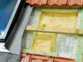 Wełna mineralna to świetny wybór, czym najlepiej ocieplić dom. Widoczna jest jej instalacja pod dachówką.