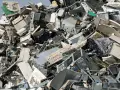 Góra starych komputerów, monitorów i klawiatur. To widok na odpady przemysłowe, które czekają na recykling.