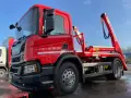Czerwony hakowiec Scania gotowy do akcji. Sprawdź, jaka jest utylizacja gruzu cena za tonę, by pozbyć się odpadów budowlanych.