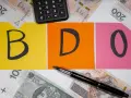 BDO - litery na kolorowych kartkach, obok kalkulator i polskie banknoty. Kto nie musi, niech nie liczy.