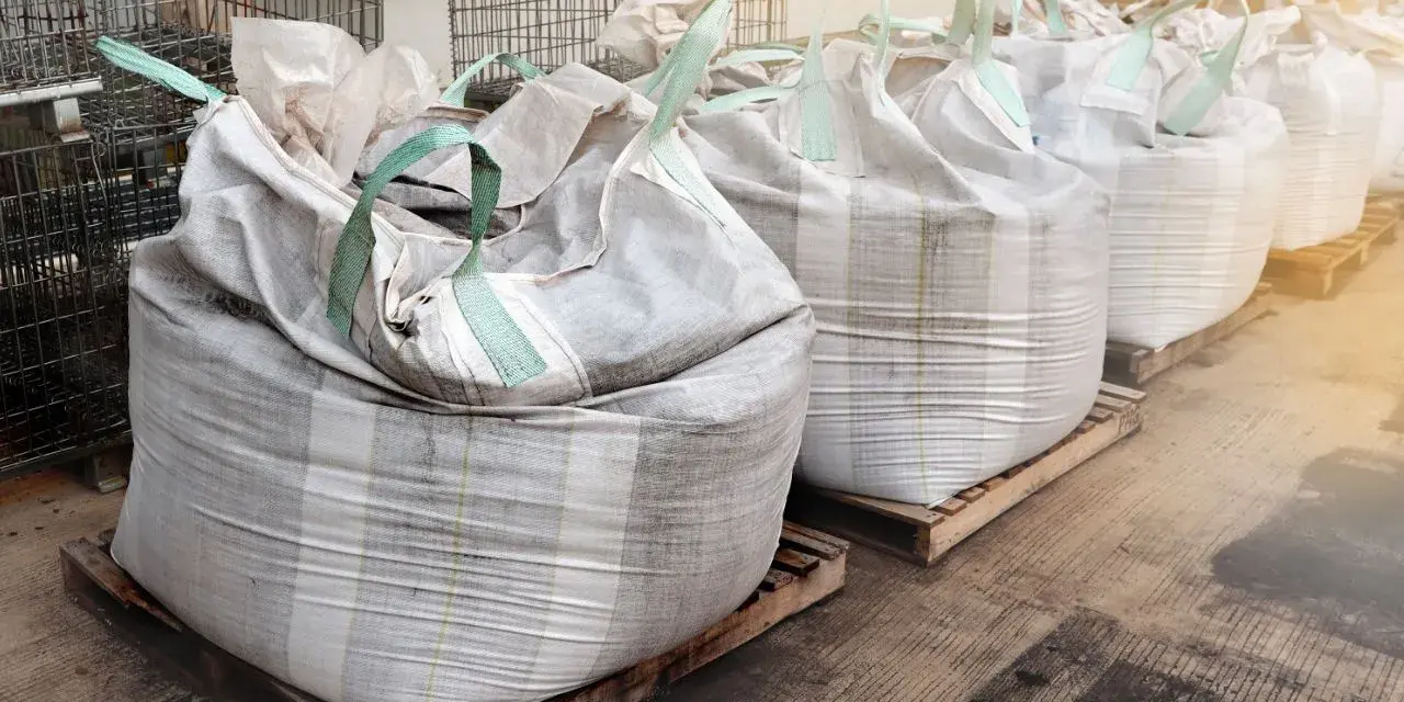 Rząd dużych worków big bag, każdy o pojemności ok. 1 m3, ustawionych na paletach.
