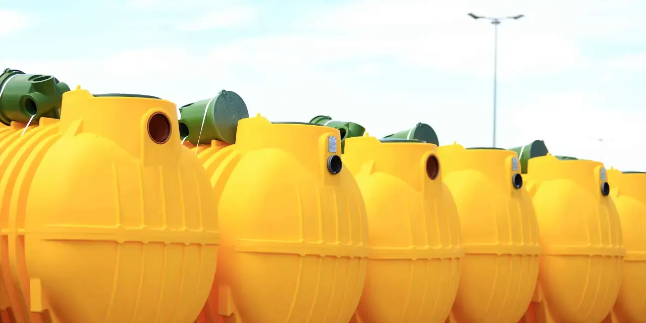 Rząd żółtych, plastikowych zbiorników na szambo ekologiczne. Czy szambo ekologiczne trzeba opróżniać? Tak, nawet te ekologiczne wymagają regularnego serwisu.