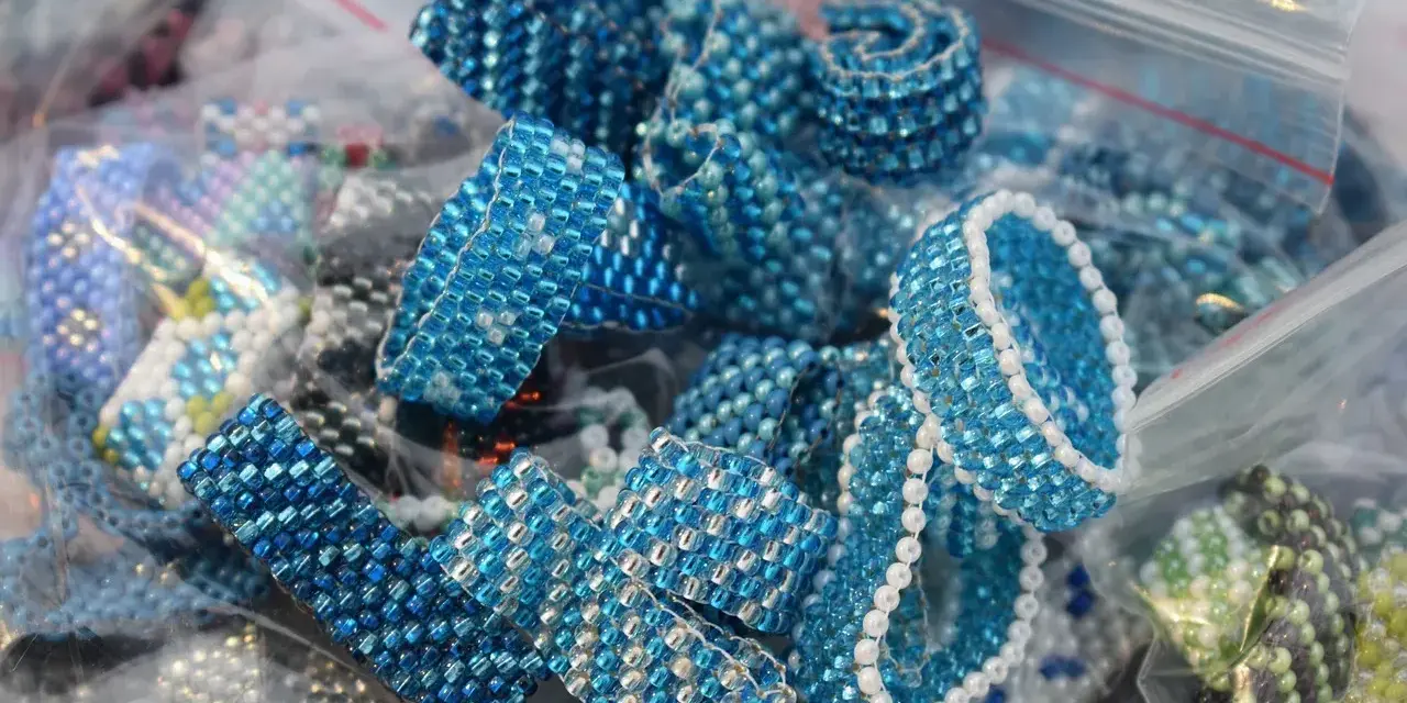 Zbliżenie na ręcznie robione pierścionki i bransoletki z niebieskich koralików w plastikowych woreczkach.
