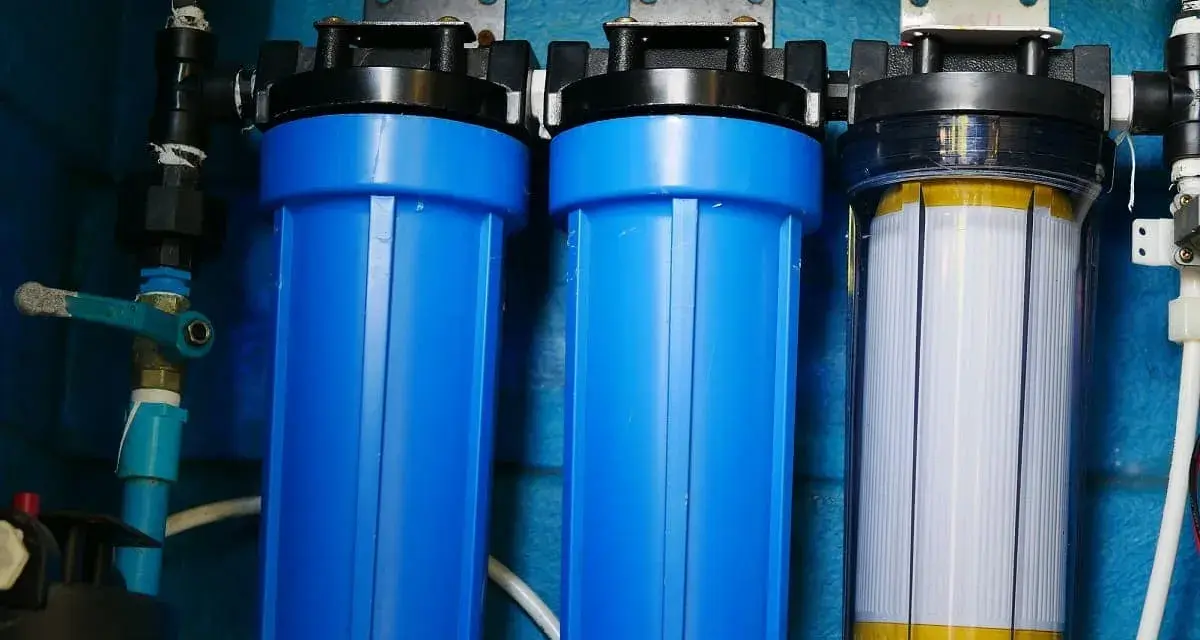 System filtrów do wody, który oczyszcza wodę. Dwa niebieskie filtry i jeden przezroczysty z białym wkładem.