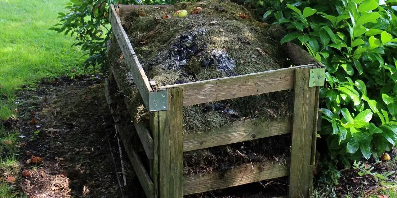 Drewniany kompostownik wypełniony trawą, liśćmi i resztkami organicznymi. To idealne miejsce na odpady zielone, kod odpadu 20 02 01.