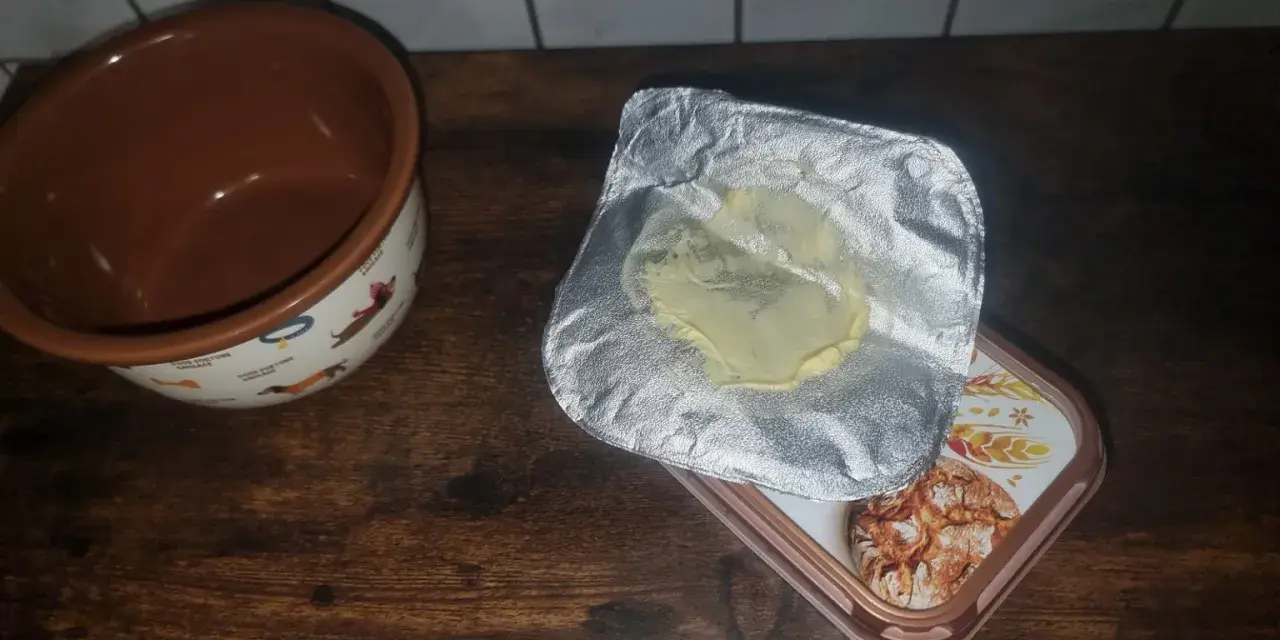 Opakowanie po maśle, które właśnie zostało zużyte, leży obok miseczki z pieskami. Gdzie wyrzucić opakowanie po maśle?