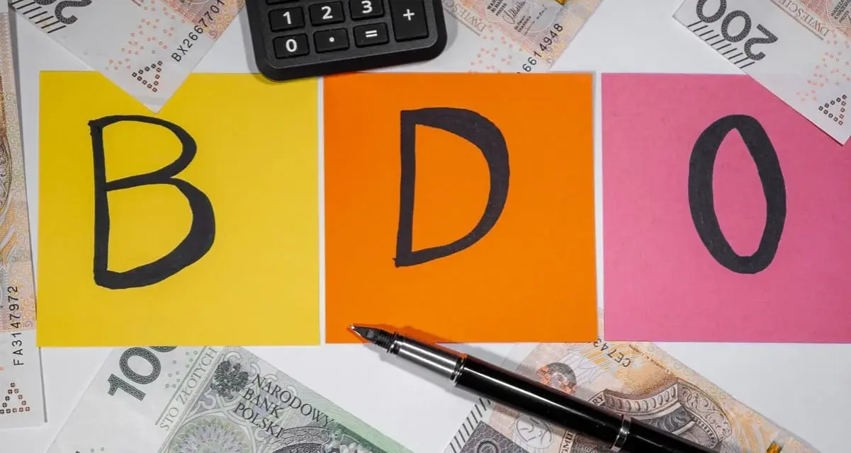 BDO - litery na kolorowych kartkach, obok kalkulator i polskie banknoty. Kto nie musi, niech nie liczy.