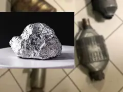 Błyszcząca bryła platyny, kluczowego składnika katalizatorów samochodowych, na białym talerzyku. Obok widoczne zużyte katalizatory.