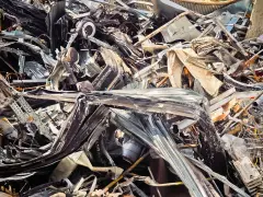 Góra poskręcanego złomu stalowego, kod odpadu 19 12 02, czeka na przetworzenie.