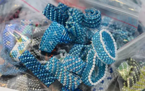 Zbliżenie na ręcznie robione pierścionki i bransoletki z niebieskich koralików w plastikowych woreczkach.