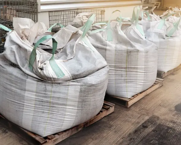 Rząd dużych worków big bag, każdy o pojemności ok. 1 m3, ustawionych na paletach.