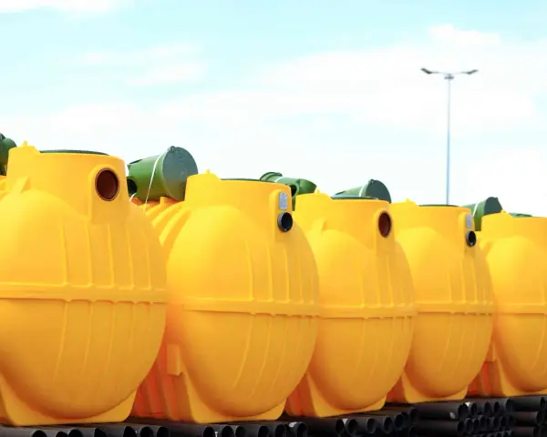 Rząd żółtych, plastikowych zbiorników na szambo ekologiczne. Czy szambo ekologiczne trzeba opróżniać? Tak, nawet te ekologiczne wymagają regularnego serwisu.