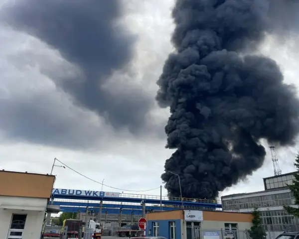 Ogromny słup czarnego dymu unosi się nad budynkami, świadcząc o pożarze wysypiska.