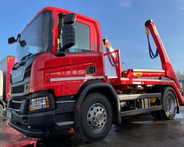 Czerwony hakowiec Scania gotowy do akcji. Sprawdź, jaka jest utylizacja gruzu cena za tonę, by pozbyć się odpadów budowlanych.