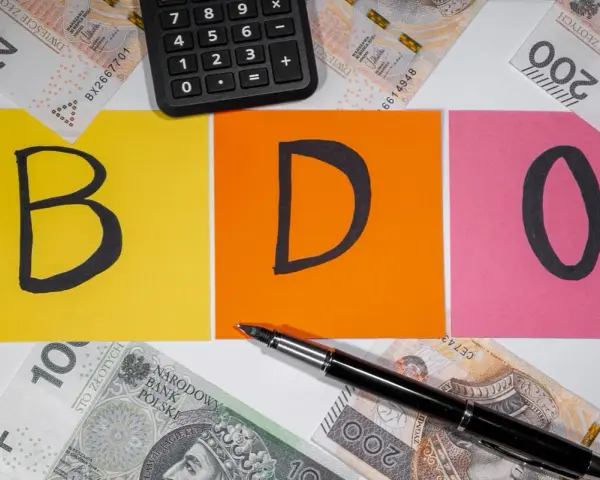 BDO - litery na kolorowych kartkach, obok kalkulator i polskie banknoty. Kto nie musi, niech nie liczy.