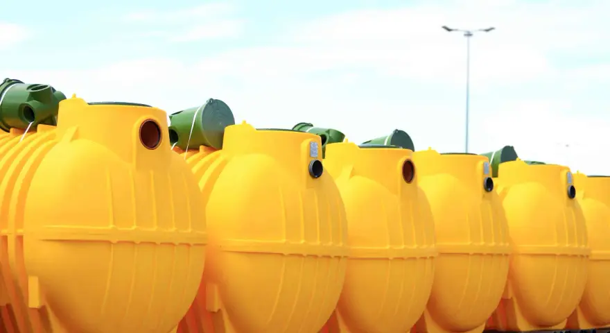 Rząd żółtych, plastikowych zbiorników na szambo ekologiczne. Czy szambo ekologiczne trzeba opróżniać? Tak, nawet te ekologiczne wymagają regularnego serwisu.