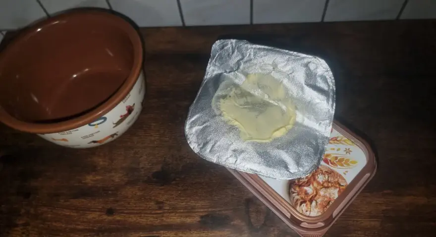Opakowanie po maśle, które właśnie zostało zużyte, leży obok miseczki z pieskami. Gdzie wyrzucić opakowanie po maśle?