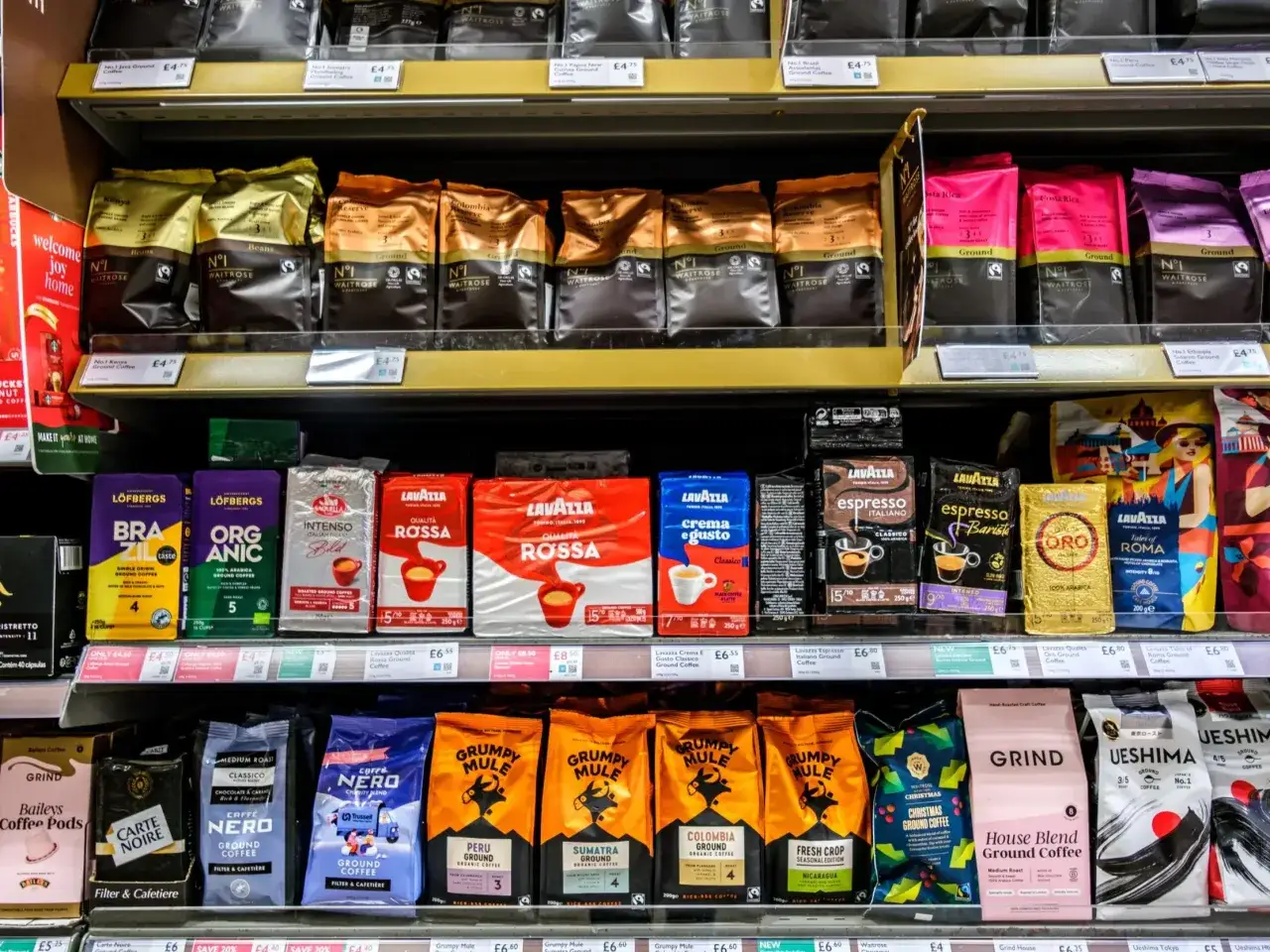 Półka z kawą mieloną. Gdzie wyrzucić opakowanie po kawie mielonej? Zazwyczaj do plastiku lub papieru, zależnie od materiału.