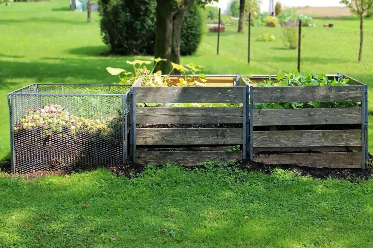 Kompostownik w ogrodzie, pokazujący domowe sposoby na przyspieszenie kompostowania. Widać różne etapy rozkładu materii organicznej.